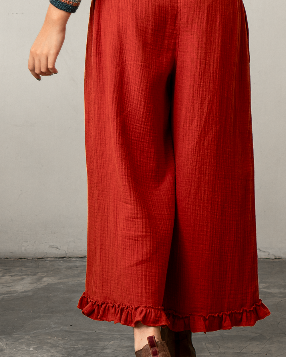Red ruffled pants worn by a person on a gray floor with a neutral background