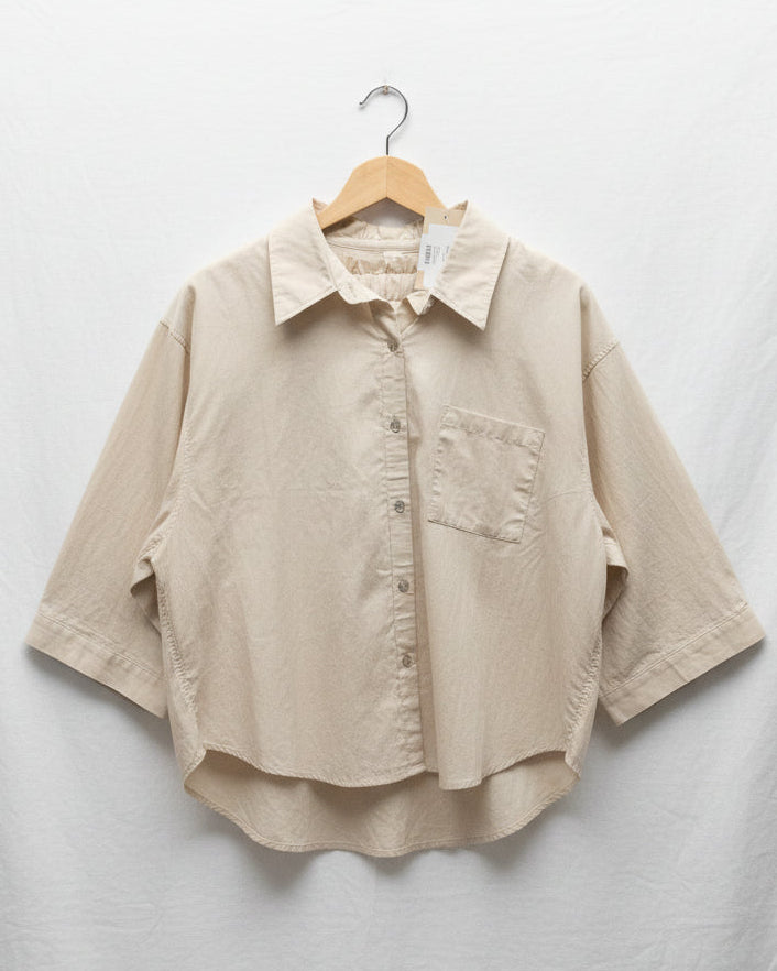 Beige shirt on a hanger against a light gray background
