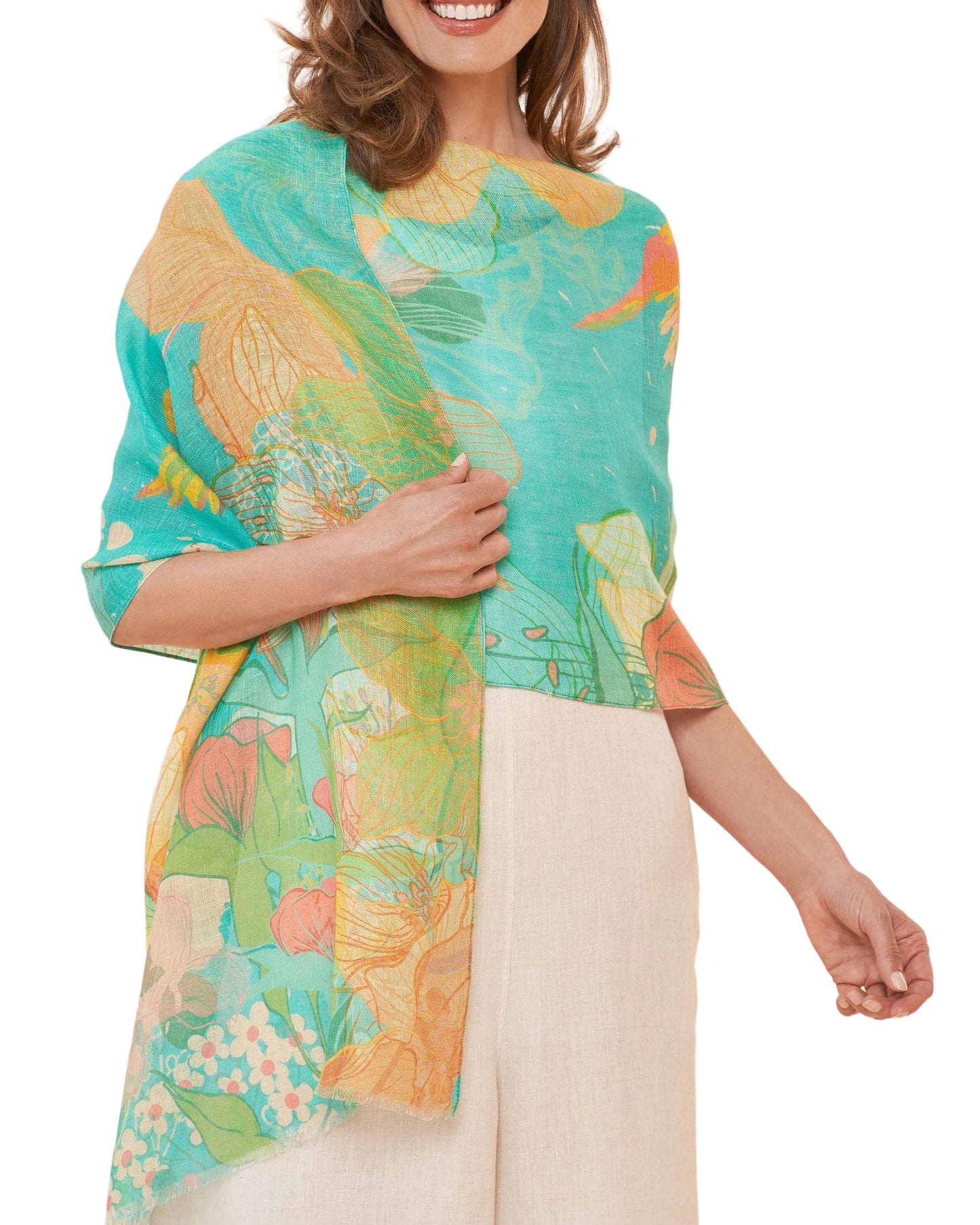 A woman wearing a printed scarf in aqua color with floral and hummingbird patterns.