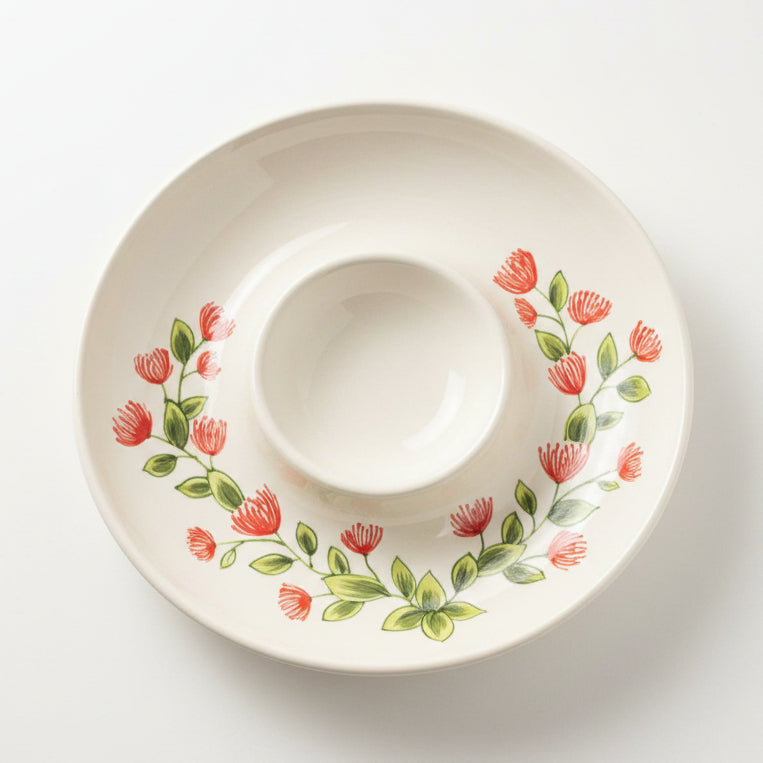 A ceramic Ohia Lehua Chip & Dip bowl with a floral pattern, primarily in red and green colors
