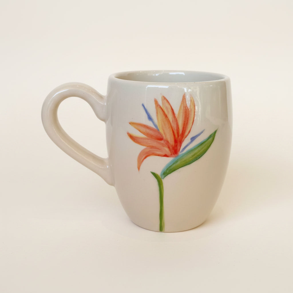 A beige ceramic barrel mug with a hand-painted tropical flower design.