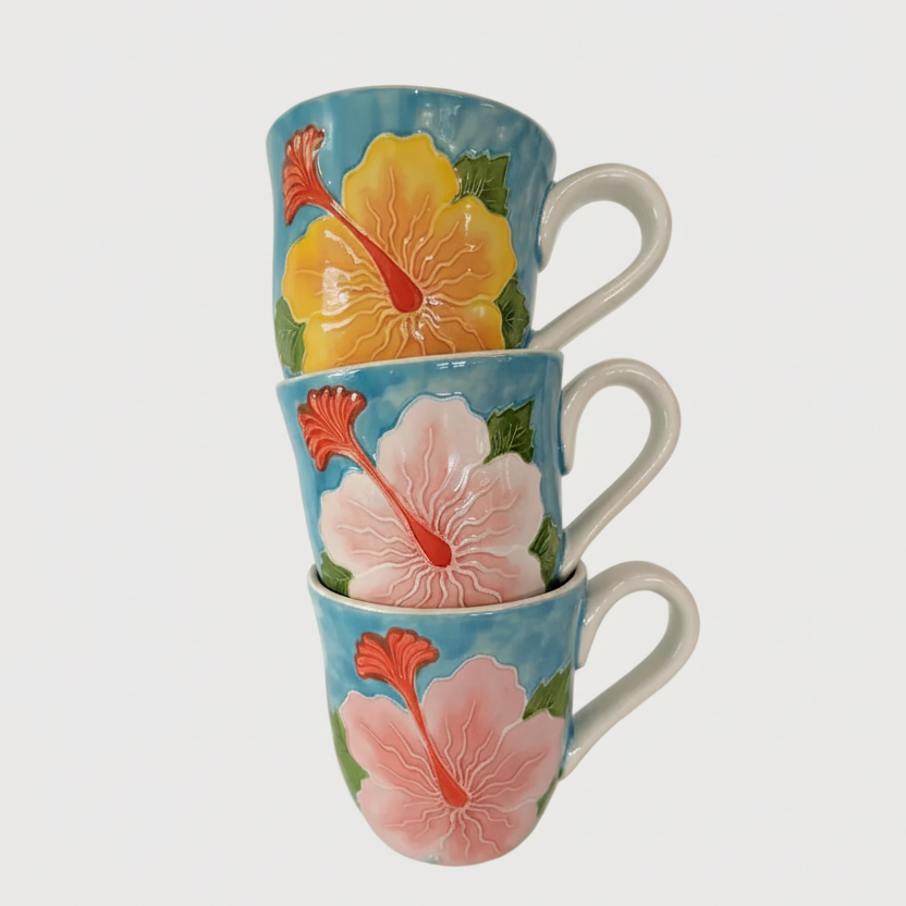 Stack of three ceramic mugs, each with a different size and design of a yellow hibiscus flower.