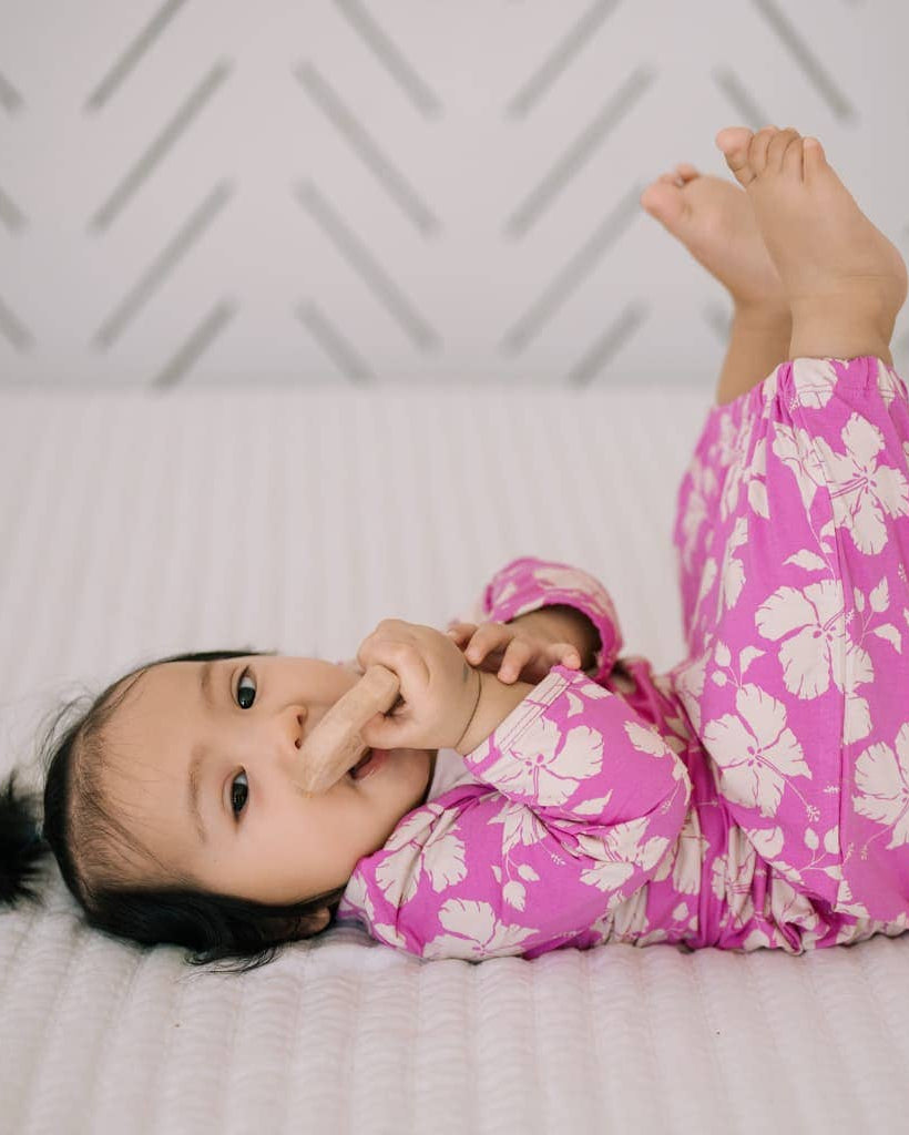 Child in pink floral pajamas lying on a bed