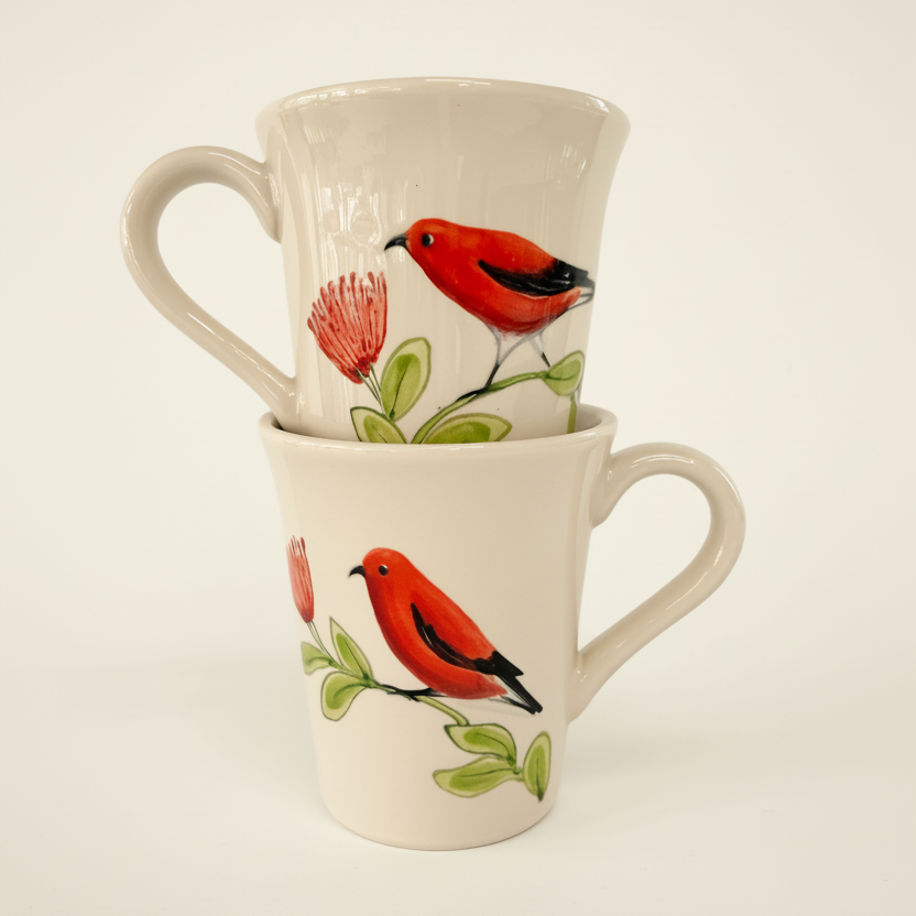 Two stacked ceramic mugs with a cream-colored glaze, decorated with a painted red bird perched on a green branch next to a pink flower.