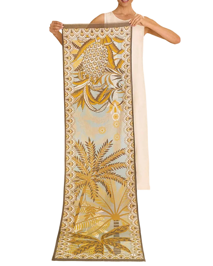 Woman holding a long, decorative scarf with palm tree design on a white background