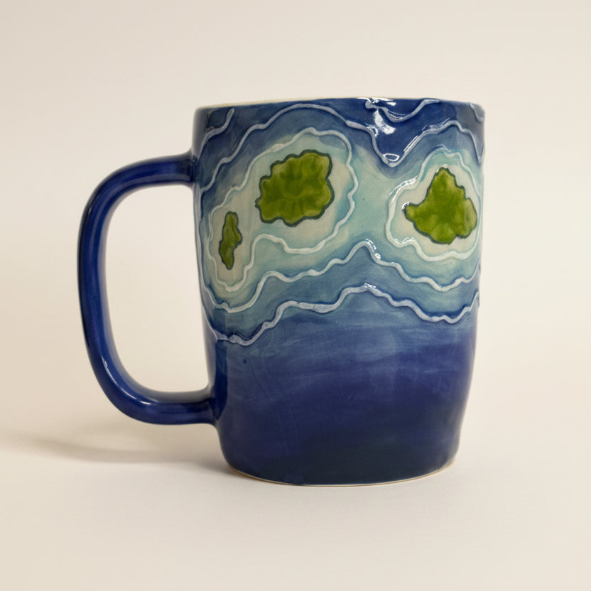 Blue mug with green and white patterns on a white background