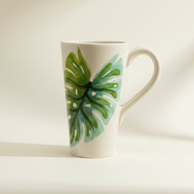 White mug with green leaf design on a white background