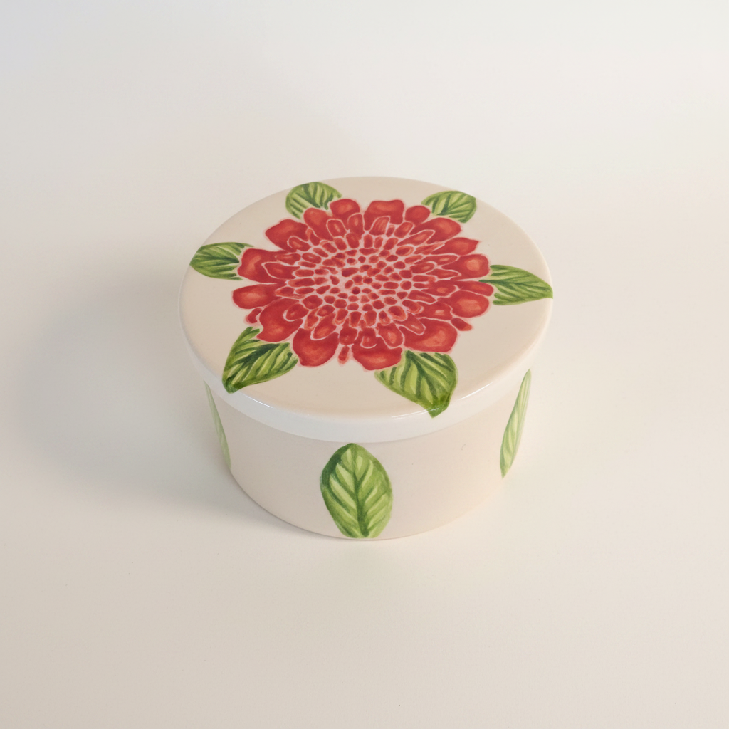 Round ceramic container with a red floral design on a white background