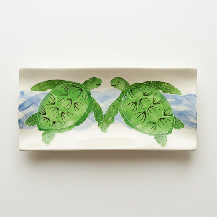 A rectangular white ceramic serving platter featuring a painted design of two green sea turtles swimming above blue water, shown on a clean white background.