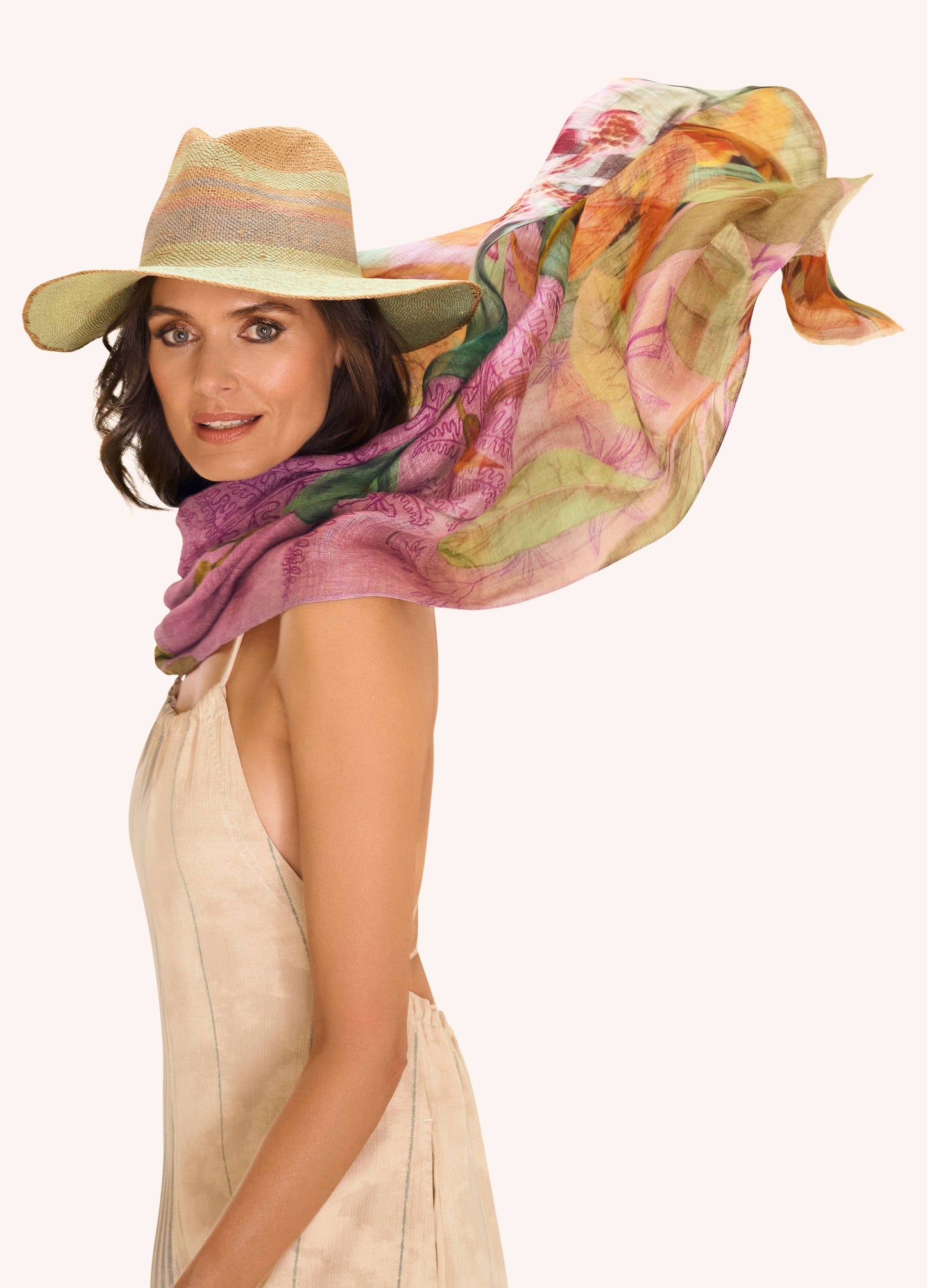Woman wearing a colorful scarf and hat on a plain background