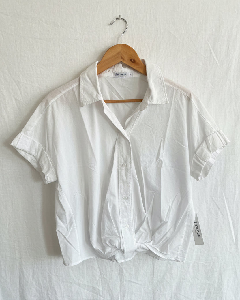 White shirt on a wooden hanger against a white background