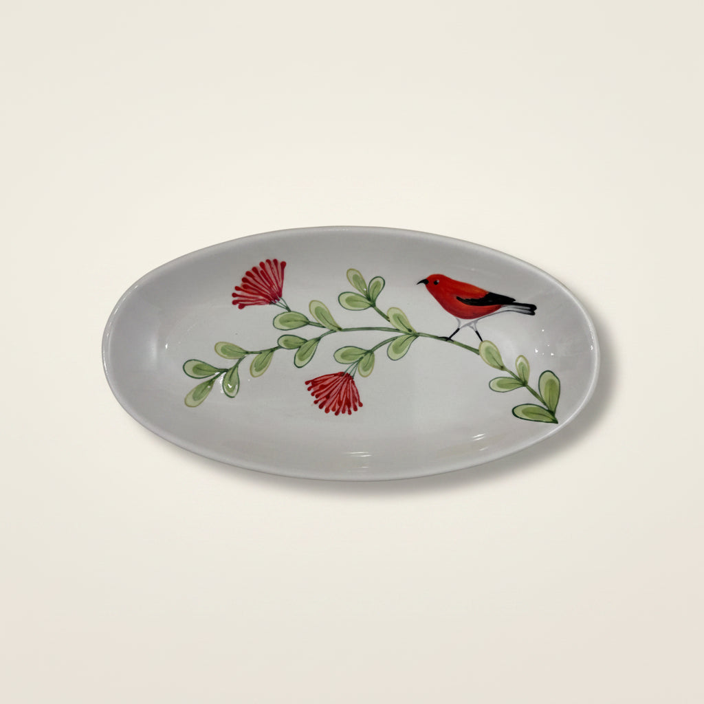 Decorative ceramic plate with a bird and floral design on a beige fabric background