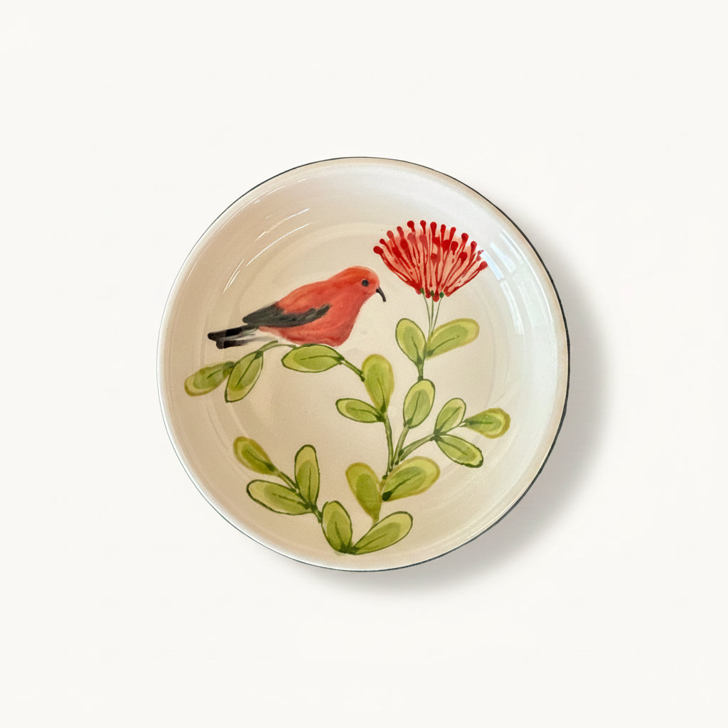 Ceramic plate with a red bird and green leaves design on a textured gray background