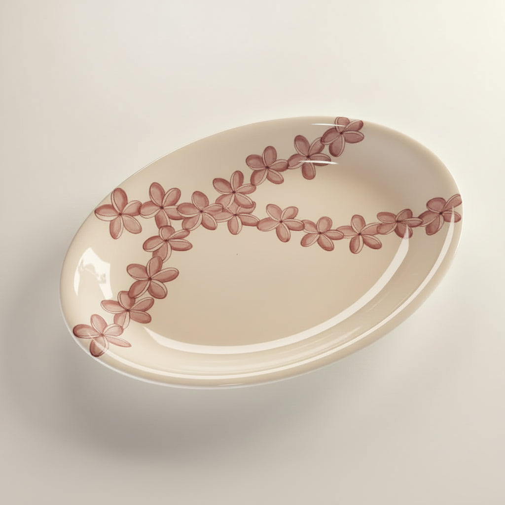 An oval-shaped beige ceramic platter with a floral pattern featuring pink and white colors