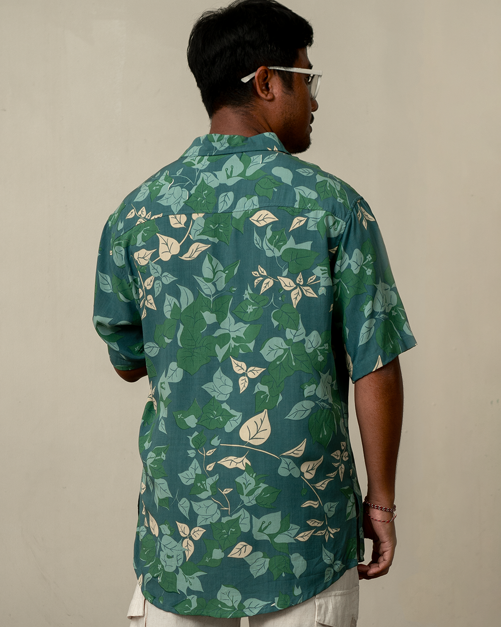 Man wearing a green floral patterned aloha shirt against a beige background