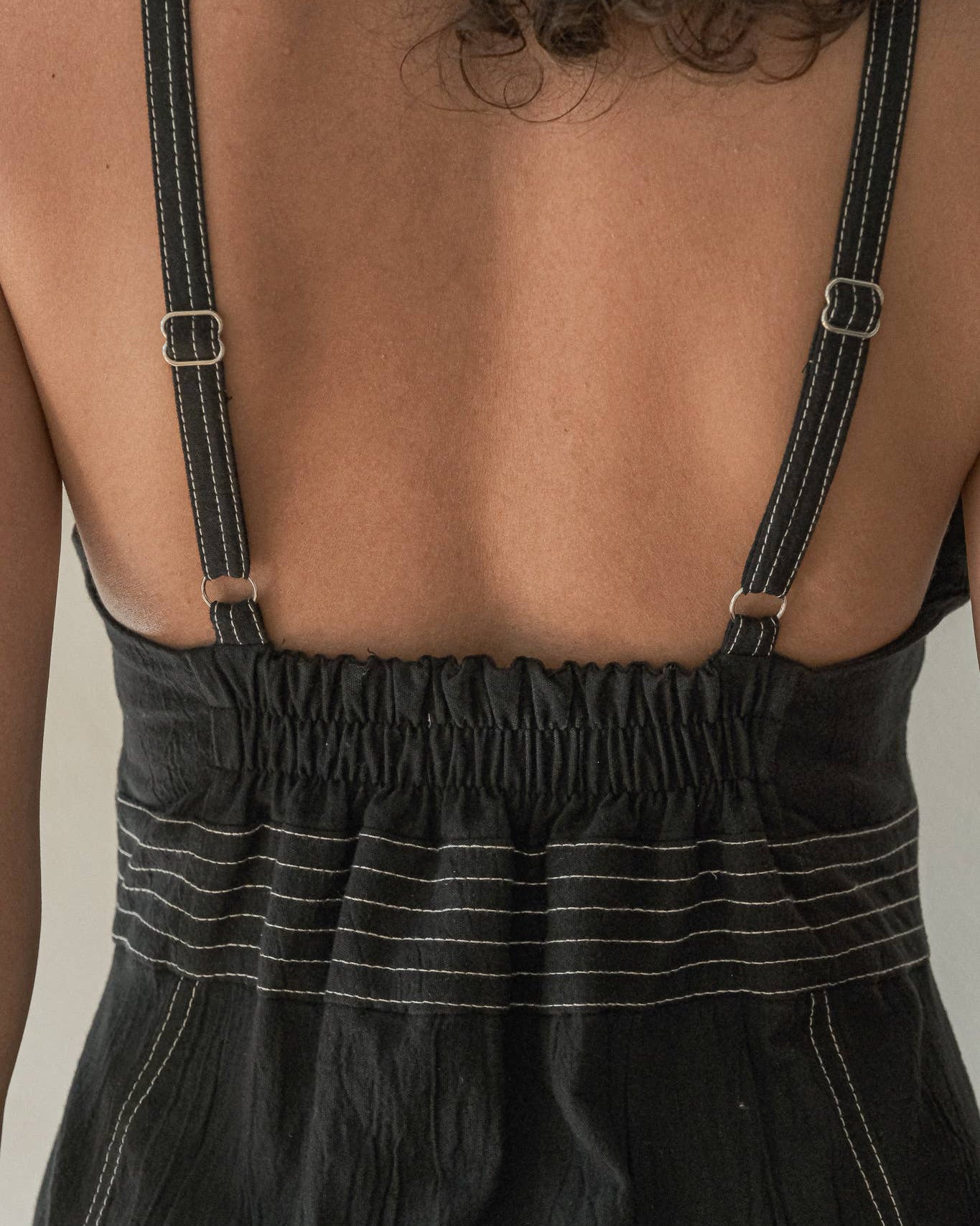 Black dress with thin straps on a neutral background