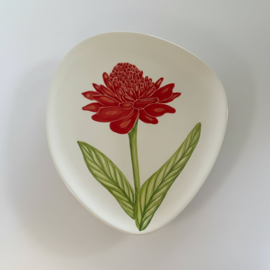 Ceramic plate with a red flower and green leaves design on a white background