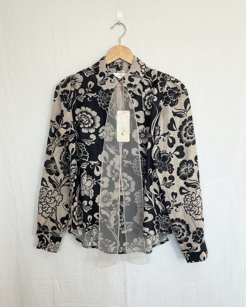 Floral patterned blouse on a hanger against a white background