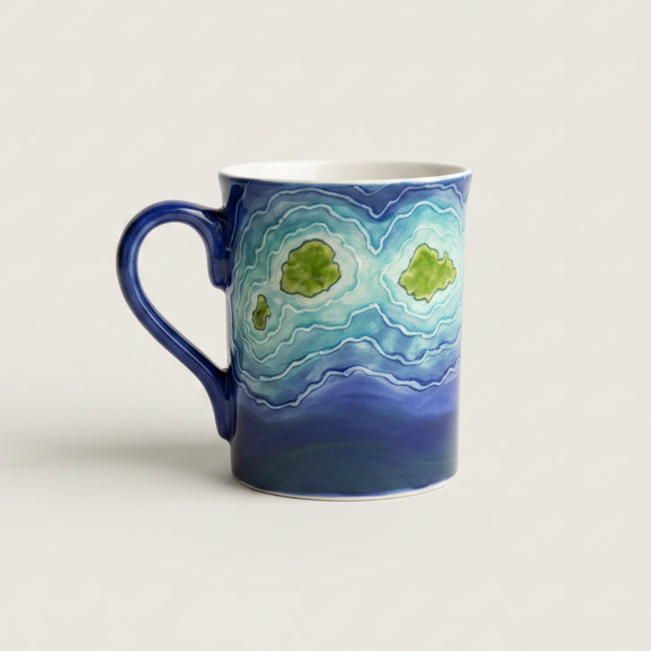 Blue mug with green pattern on a textured surface