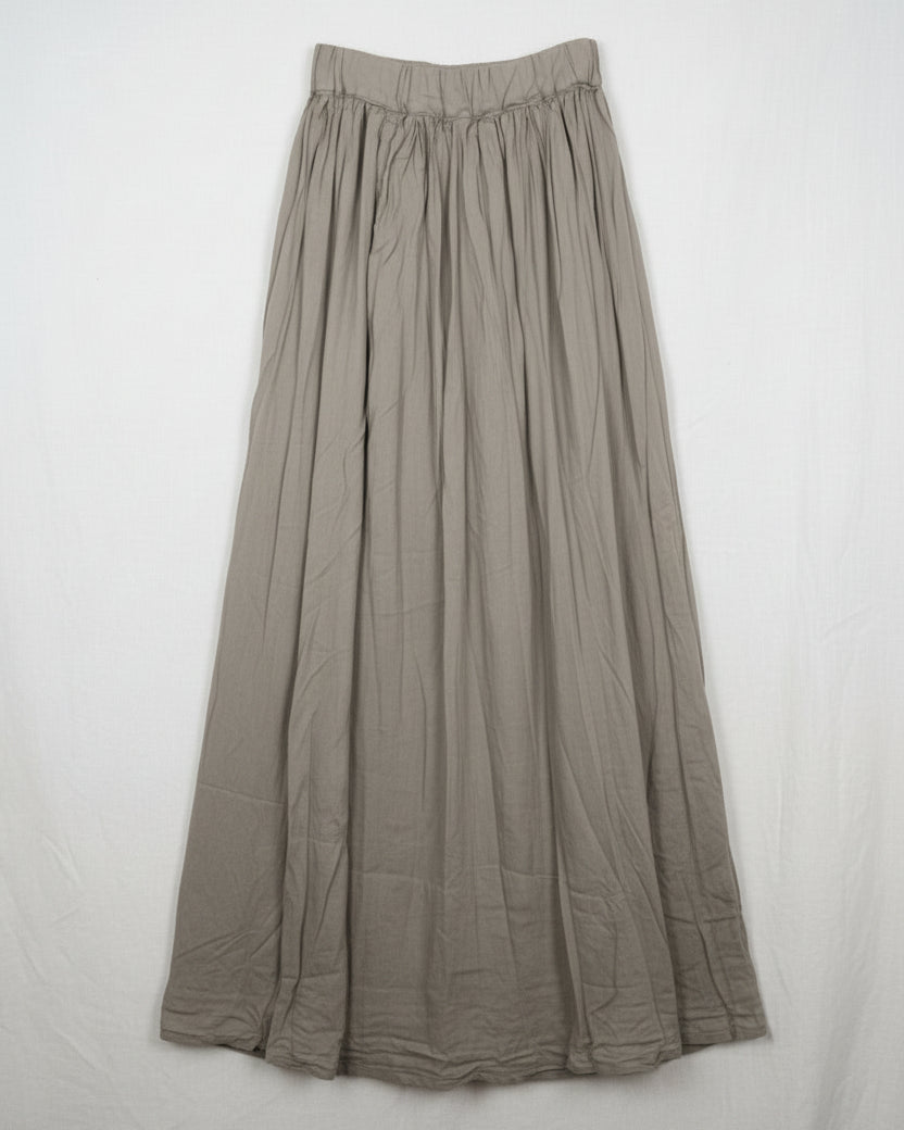 A sage green cotton silk skirt hanging on a wooden hanger
