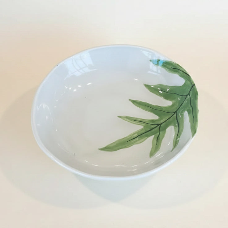 Ceramic bowl with a green leaf design on a white background