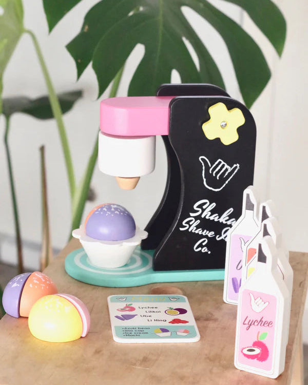Toy shave ice maker set with colorful shave ice and packaging on a wooden surface.