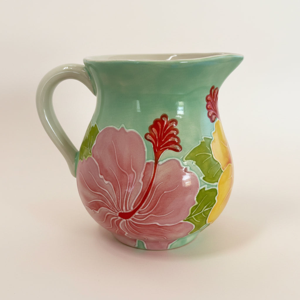 Decorative ceramic creamer with floral design on a light gray background