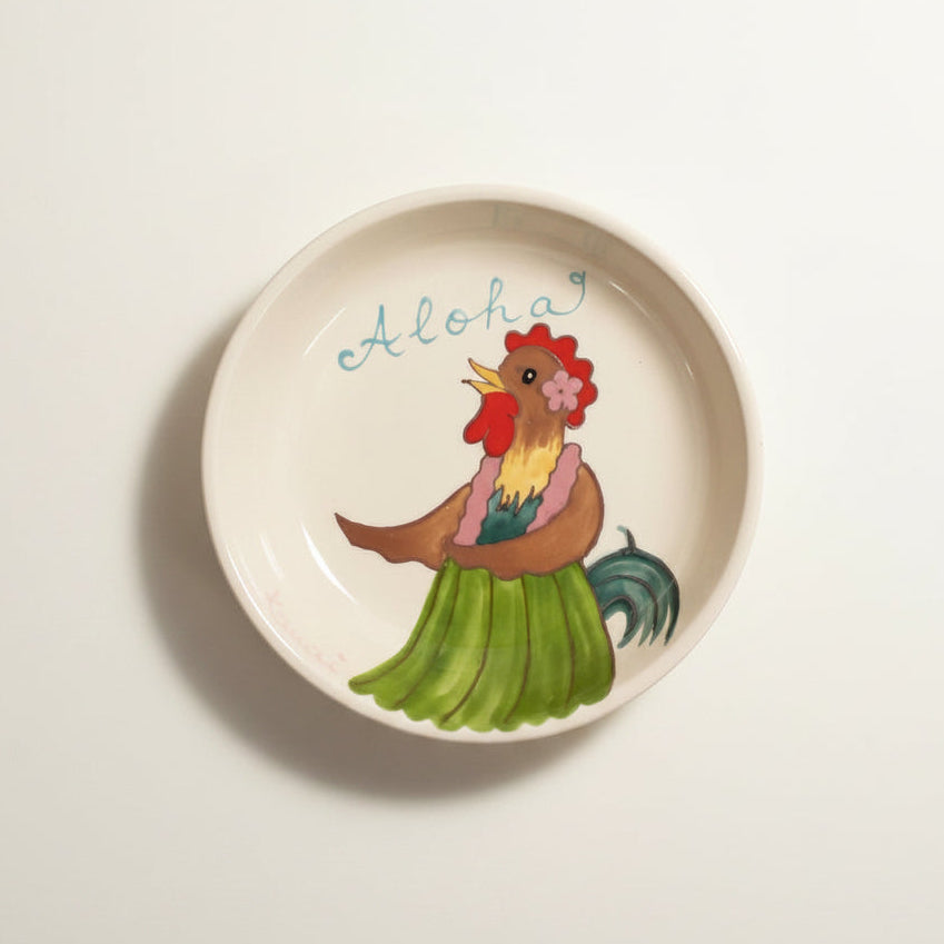 Ceramic plate with a rooster design and 'Aloha' text on a white background