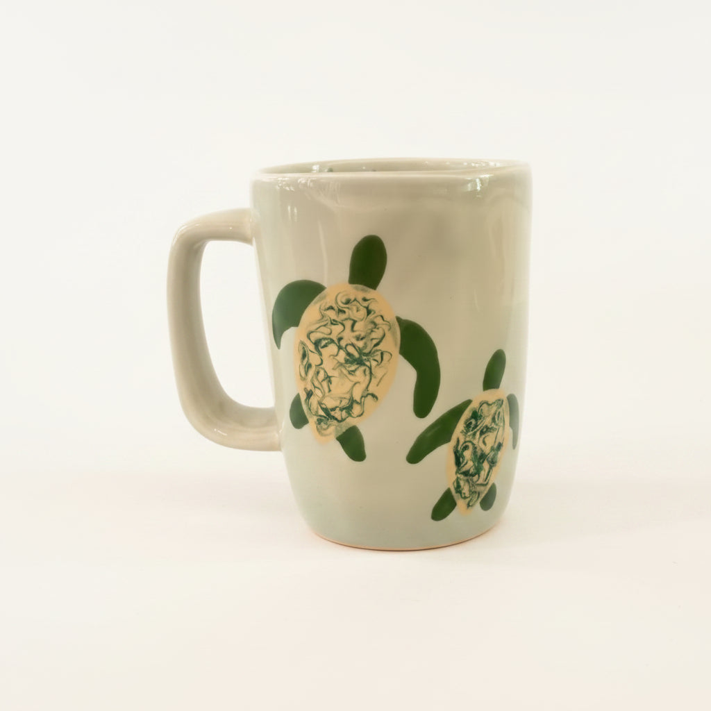 White mug with green turtle design on a white background