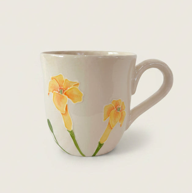 A white ceramic mug with hand-painted yellow puakenikeni designs on the side