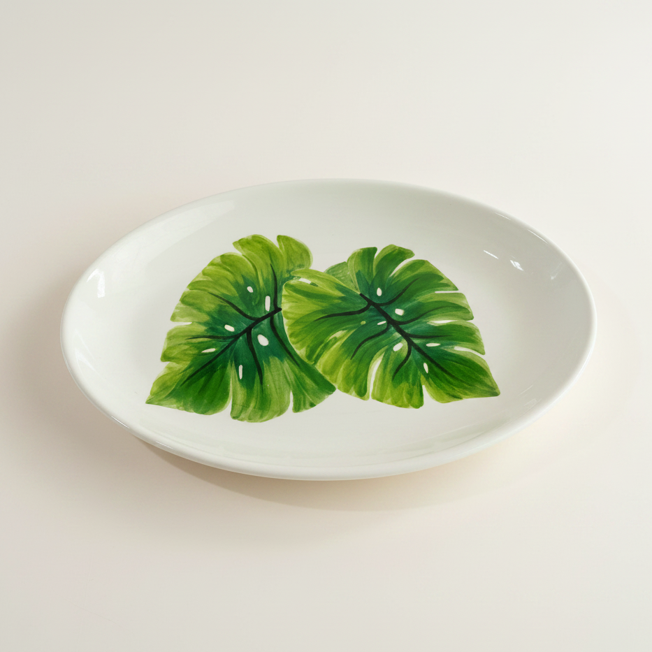Oval ceramic dish with green leaf design on a white background
