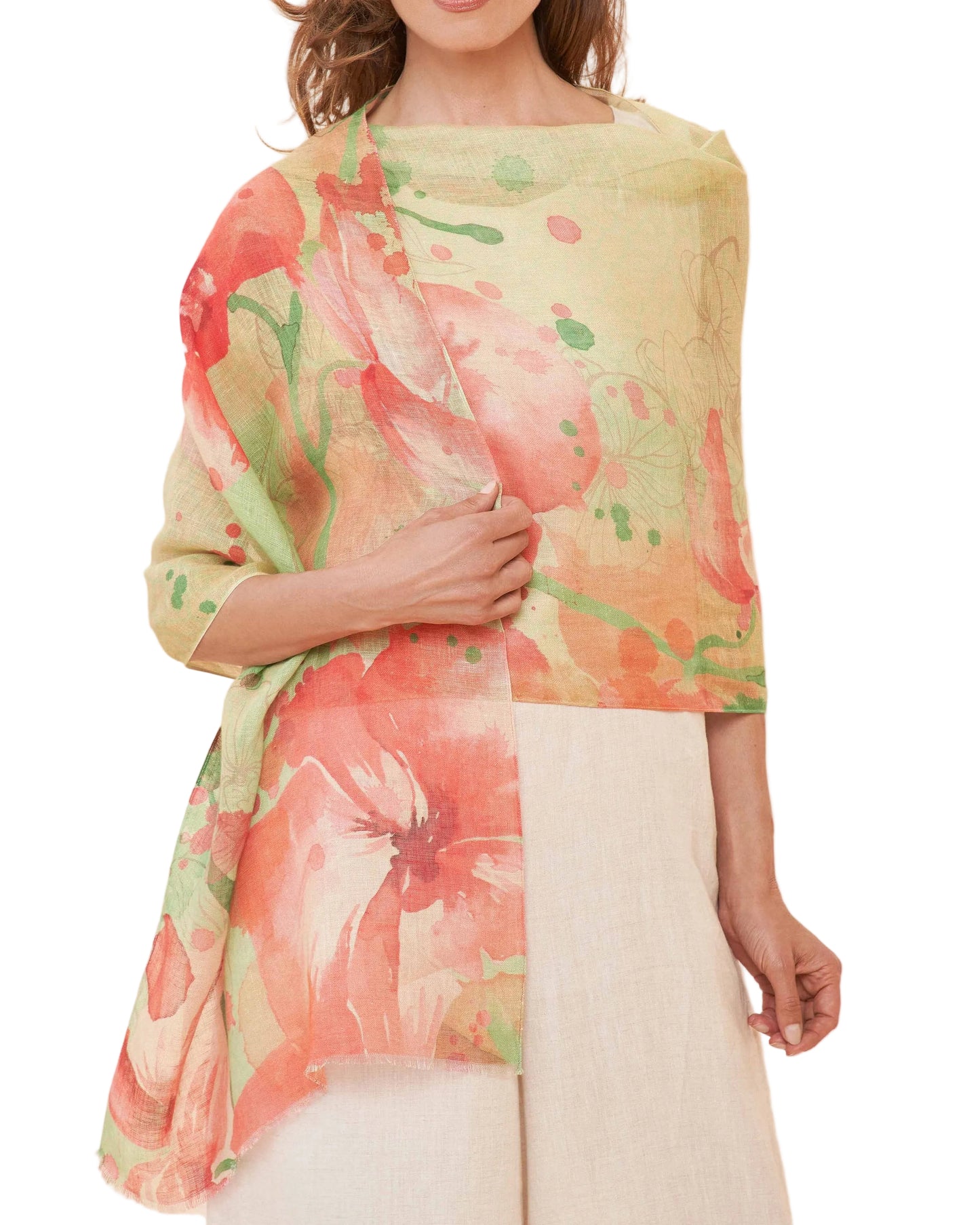 A woman wearing a lightweight, multicolored floral linen scarf draped over her shoulders, with a beige top and white pants.