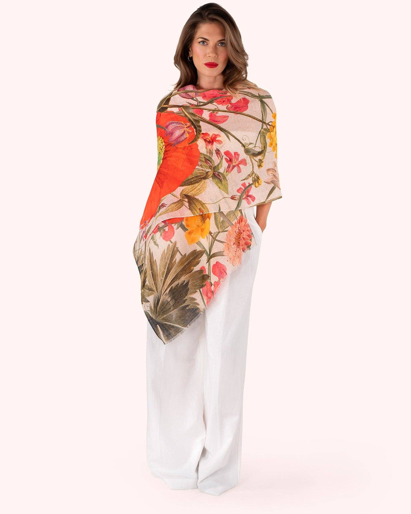 Woman wearing a floral patterned scarf with white pants on a white background