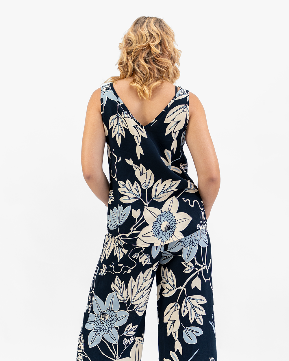 Woman wearing a navy floral top and pants on a white background