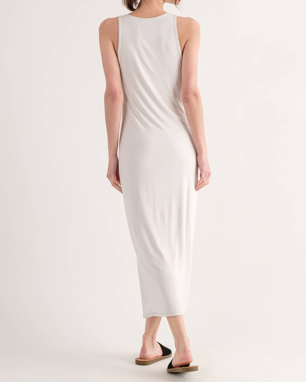 Woman wearing a white sleeveless dress on a plain background
