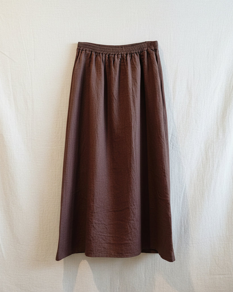 Brown skirt hanging on a wooden hanger against a light wooden panel background