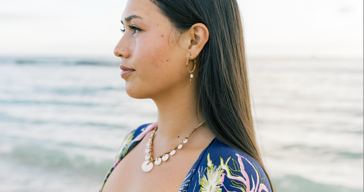 Woman at the beach wearing earrings and necklace in a blue robe