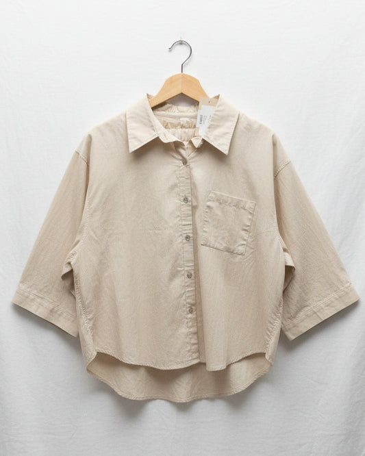 Beige shirt on a hanger against a light gray background
