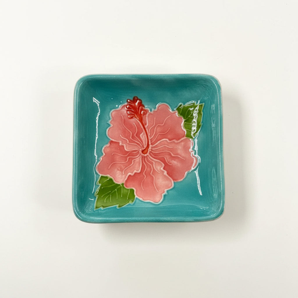 Ceramic plate with a pink flower design on a teal background