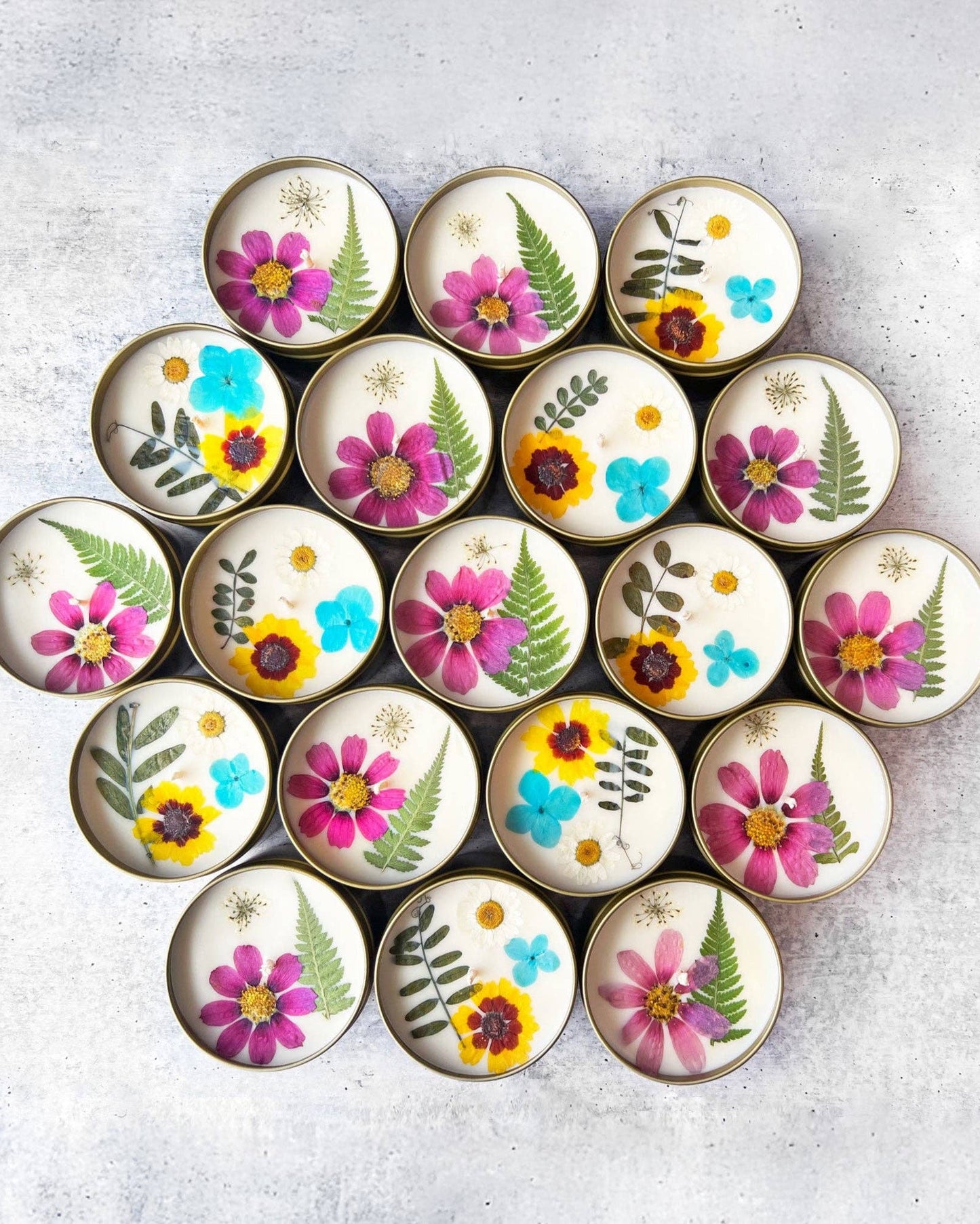 Circular candles with floral and leaf designs arranged in a circular pattern on a light gray surface.