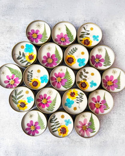 Circular candles with floral and leaf designs arranged in a circular pattern on a light gray surface.
