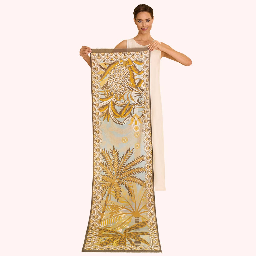 Woman holding a long, decorative scarf with palm tree design on a white background