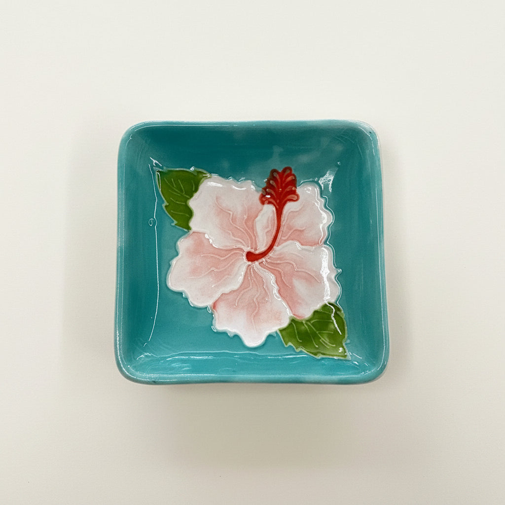 Ceramic plate with a pink flower design on a teal background