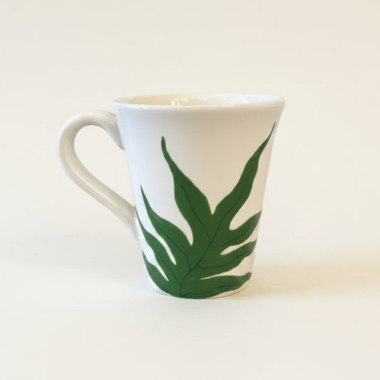 White mug with green leaf design on a white background