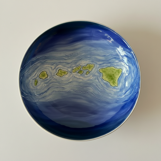 A hand-painted ceramic pasta bowl with a design depicting the Hawaiian island chain in shades of blue and green.