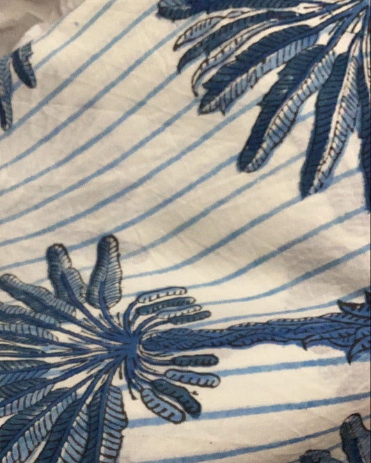 Close-up of a pareo sarong with a palm tree pattern in blue on a white striped background.