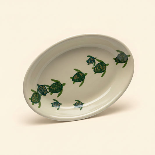An oval-shaped ceramic platter with a green and beige turtle pattern