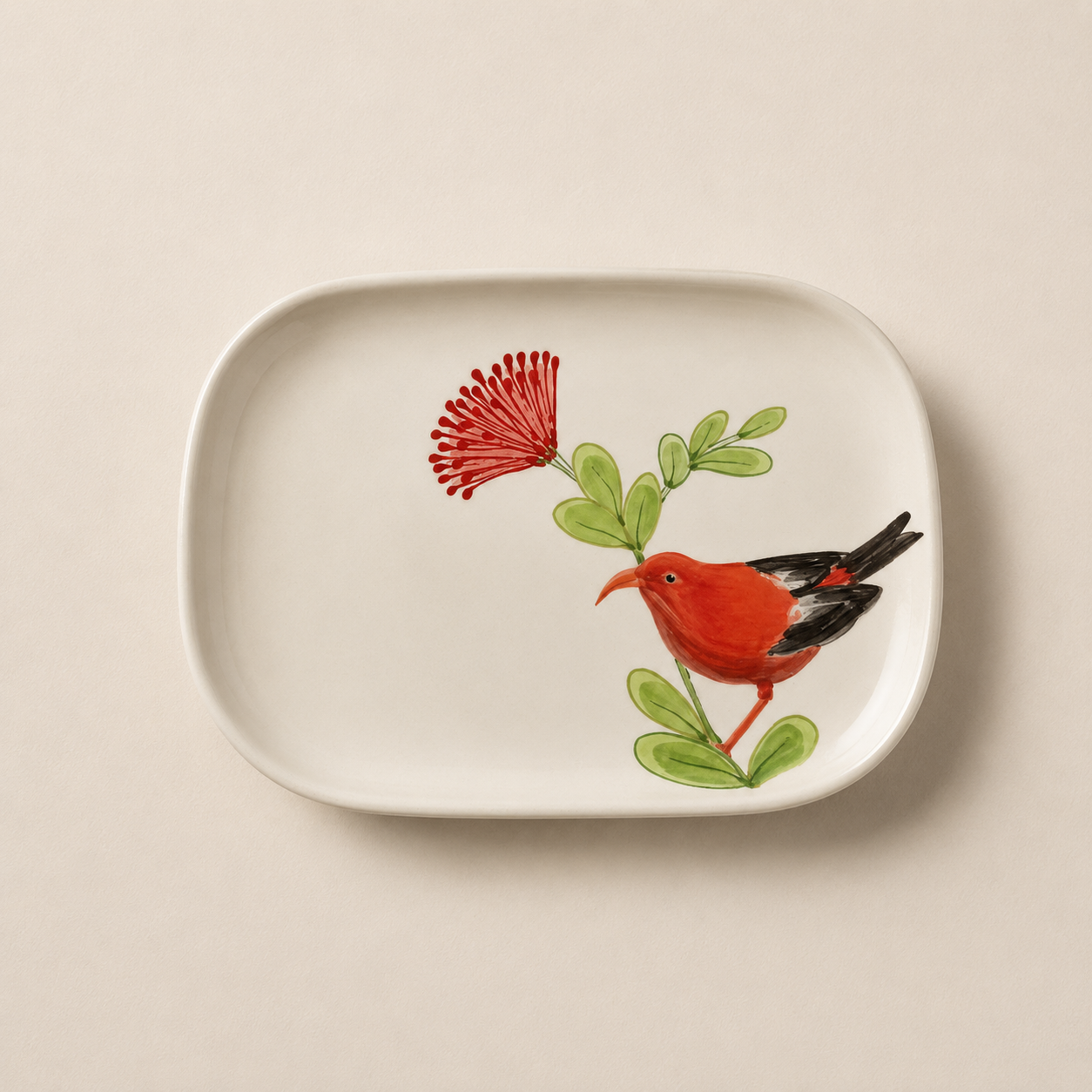 A white rectangular ceramic serving platter with rounded corners, featuring a hand-painted illustration of a red bird perched on a green leafy branch next to a red flower, set against a warm beige background.