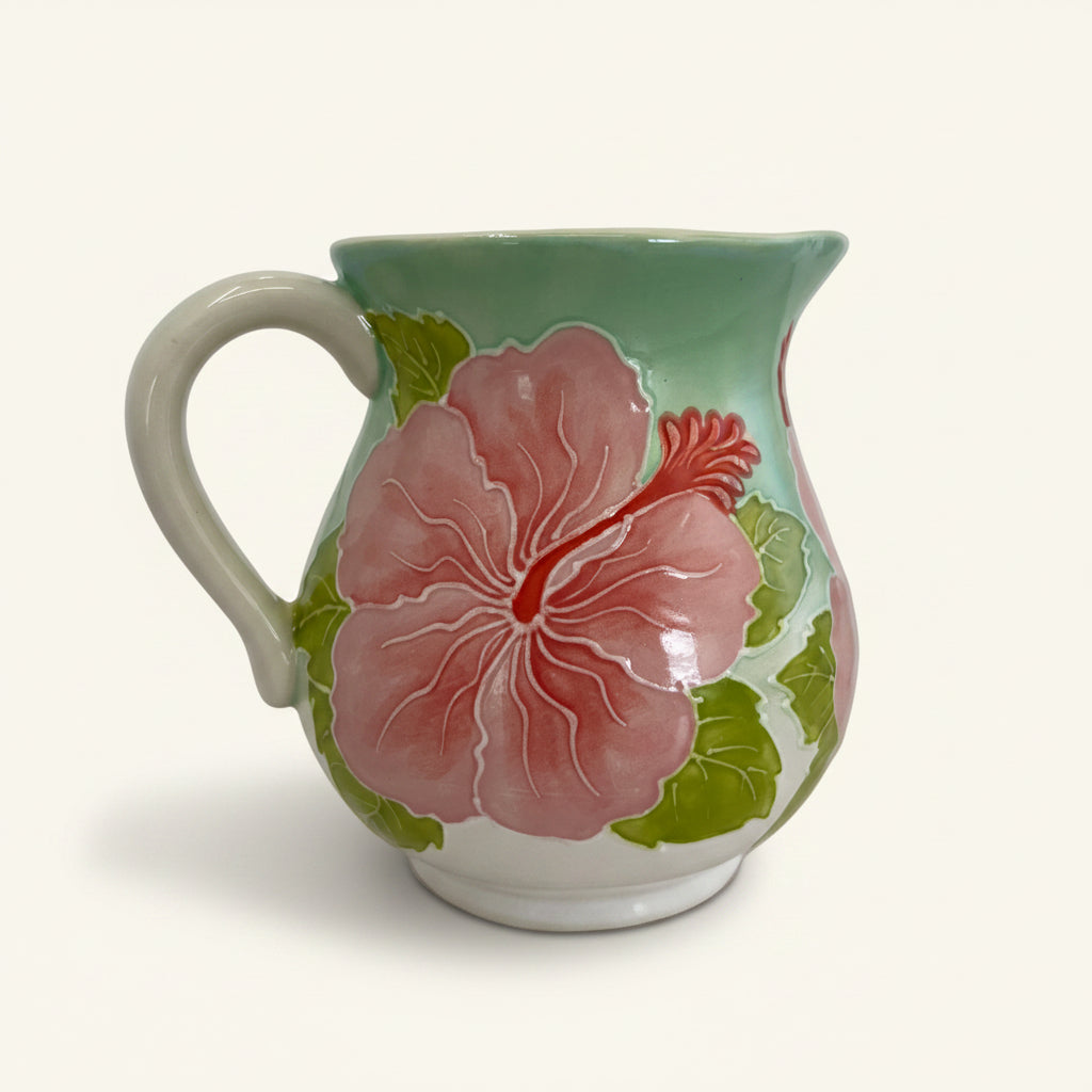 Ceramic creamer with pink floral design on a white background