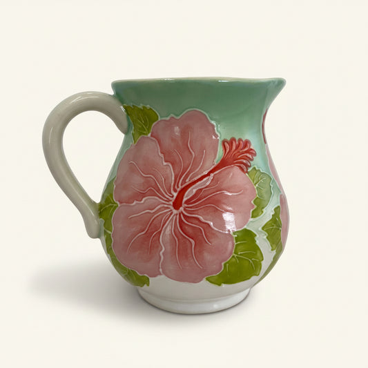 Ceramic creamer with pink floral design on a white background